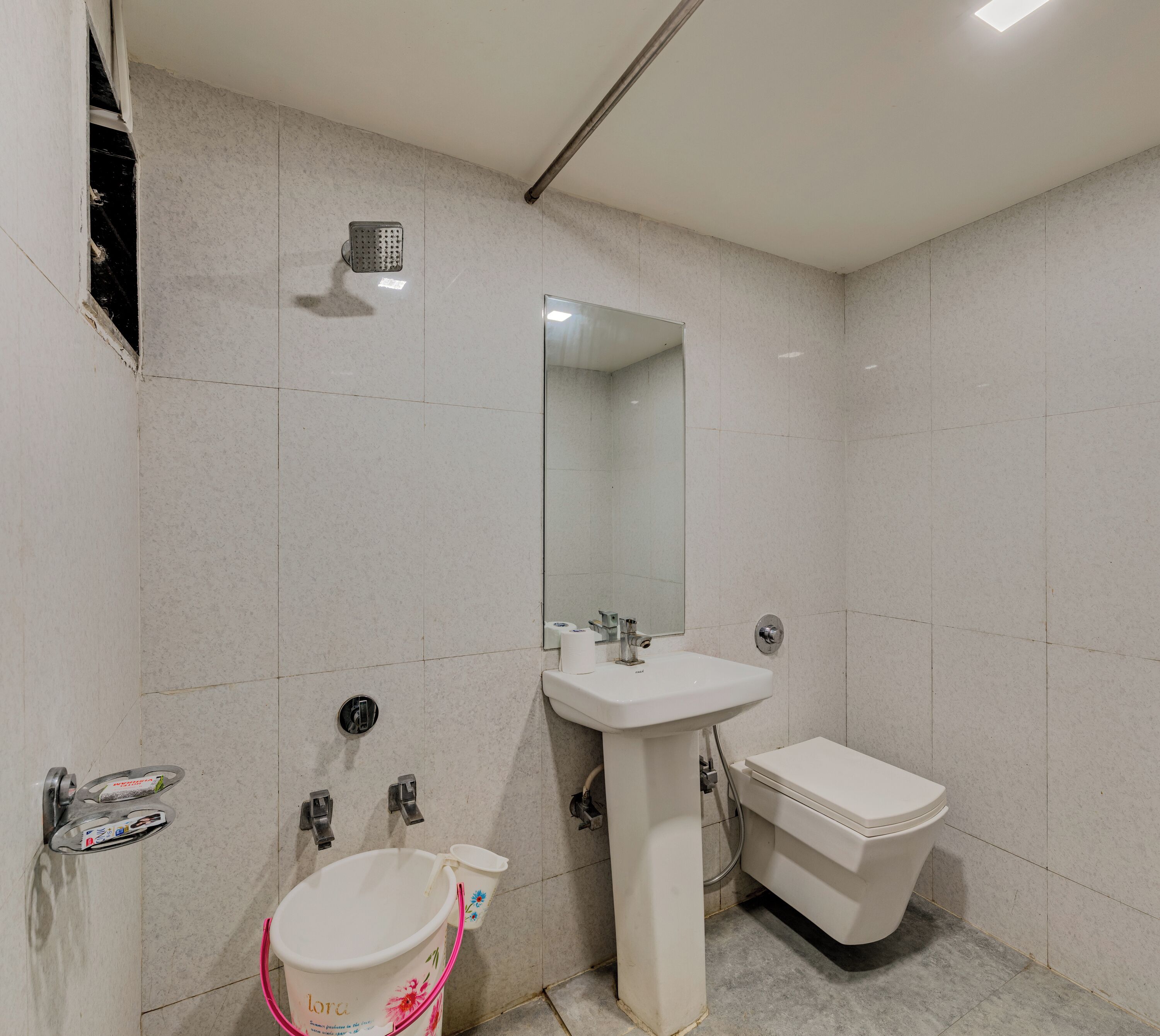 Un baño con lavamanos blanco, espejo, inodoro y ducha.