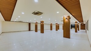 Een ruimtelijk, goed verlicht interieur met een hoge nok en houten balken.