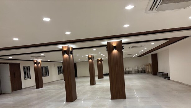 Een ruime, goed verlichte hotellobby met een modern design, met een gepolijste marmeren vloer en houten pilaren.
