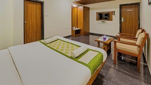 Een hotelkamer met een bed, een bureau, een stoel, een televisie en een plafondventilator.
