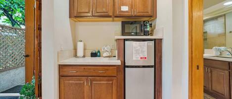 A compact kitchen with wooden cabinets, a stainless steel refrigerator, and a microwave.