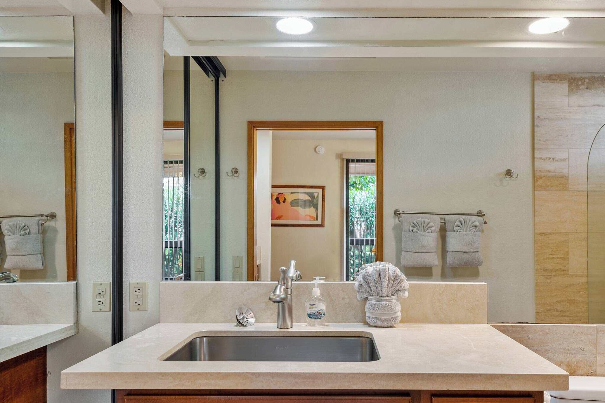 A modern bathroom with a large mirror, a sink with a faucet, and a towel rack.