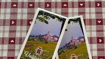 Zwei Postkarten mit Landschaft und Kirche vor einem karierten Stoffhintergrund.