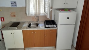 A compact kitchen with a sink, a stove, and a refrigerator. - Rozalia Studios  (Sivota)