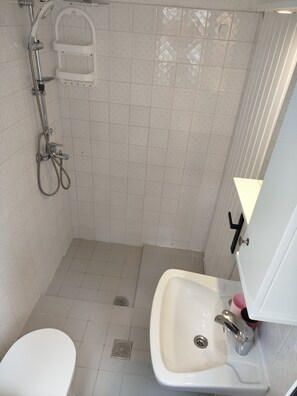 A bathroom with a shower, toilet, and sink.