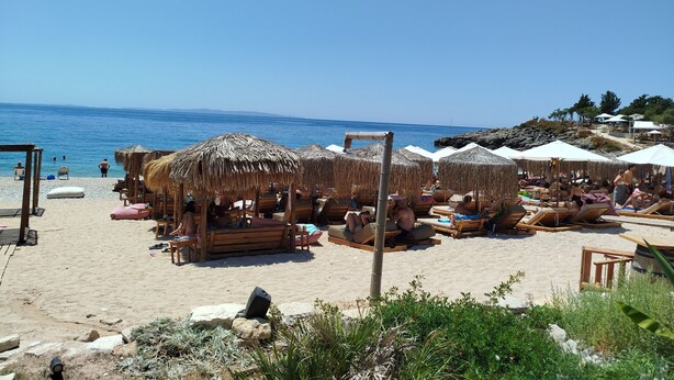 A beach with thatched umbrellas and wooden lounge chairs. - Rozalia Studios  (Sivota)