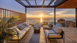 A rooftop terrace with a sunset view, a wooden pergola, and a seating area with cushions and a coffee table. - Azure Horizon Gas Heated Pool With Stunning View (Melbourne)