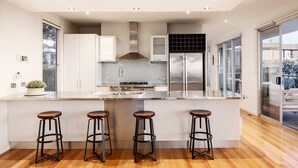 Een moderne keuken met een centraal eiland, roestvrijstalen apparatuur en een groot raam.