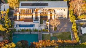 Een modern huis met twee verdiepingen, een zwembad, een overdekt terras en een verzorgde tuin.