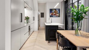 Une cuisine moderne dotée d’un plan de travail en marbre, d’un évier et d’un coin repas avec une table et des chaises en bois.