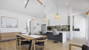 A modern kitchen with white cabinets, a central island, and pendant lighting. - Saltwood Coastal Hamptons Luxe With Pool (Melbourne)