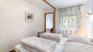 Ein Schlafzimmer mit zwei Betten, einem Heizkörper, einem gerahmten Bild an der Wand und einem Fenster mit Vorhängen.
