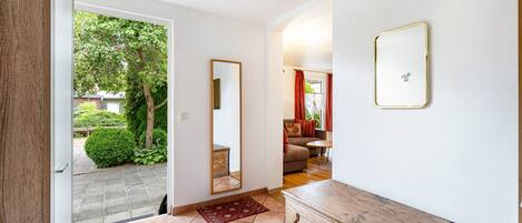 A hallway with a wooden dresser, a mirror, and a red rug.
