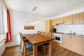 Une cuisine moderne avec des meubles de rangement en bois, une table à manger avec des chaises et un luminaire suspendu.