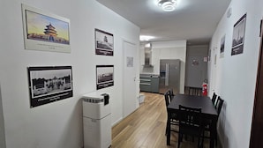 A narrow hallway with a dining area featuring a table and chairs, a refrigerator, and a wall-mounted air conditioner. - Orienty Home Pentacoro (Trieste)
