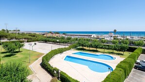 Une piscine avec vue sur la mer, entourée de verdure et disposant d’un espace de stationnement.
