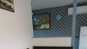 Zona pranzo con tavolo in legno e sedie nere, una panca, un quadro appeso al muro e una sveglia.