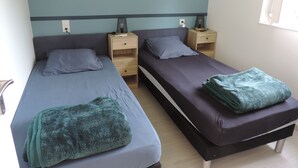 Camera matrimoniale con due letti singoli, ognuno con cuscino e un comodino.