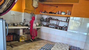 A kitchen with a tiled backsplash, a water heater, and shelves with kitchenware.