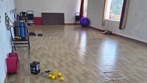 A spacious room with a wooden floor, exercise equipment, and a large window.