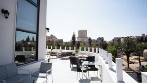 A rooftop terrace with outdoor seating, large windows, and a city view.
