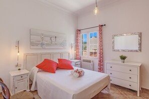 A bedroom with a bed, a nightstand, a dresser, a mirror, and a painting on the wall.