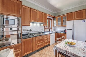 A kitchen with wooden cabinets, stainless steel appliances, a tiled backsplash, and a dining table with a placemat.