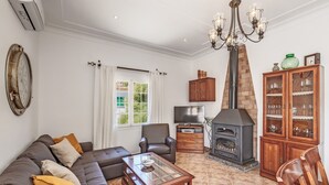 A living room with a sofa, armchair, coffee table, fireplace, TV, and a cabinet with glassware.