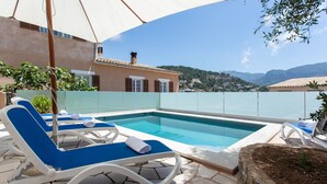 A pool area with lounge chairs and a view of the surrounding landscape.
