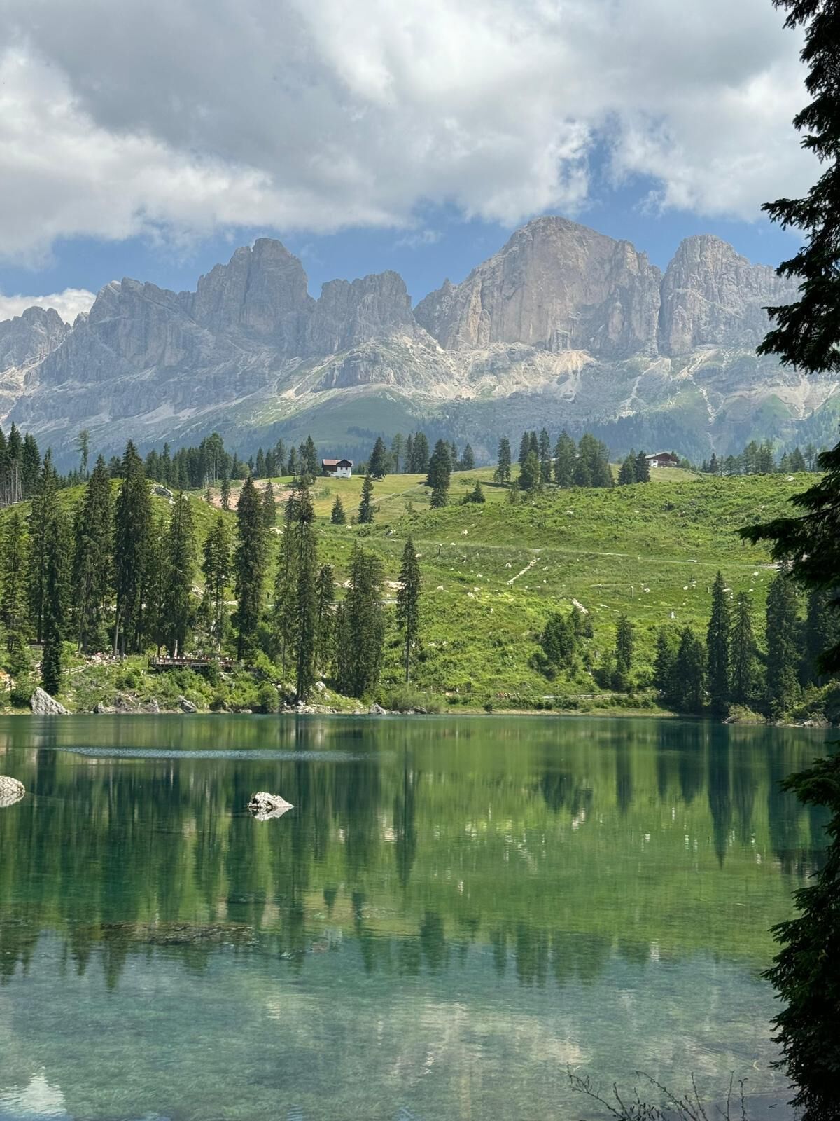 A mountainous landscape with a lake, trees, and a small house.