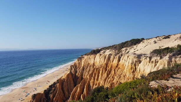 Eine Küstenlandschaft mit Sandstrand und einer steilen Klippe.