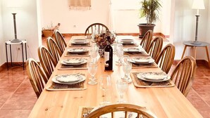Ein Esszimmer mit Holztisch, gedeckt für sechs Personen, umgeben von Stühlen, mit einer hängenden Leuchte darüber.