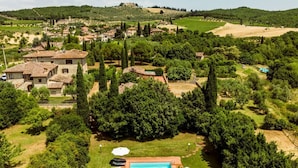 Eine Villa mit Swimmingpool, umgeben von Bäumen und einem Weinberg im Hintergrund.