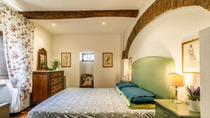 A bedroom with a bed, dresser, lamp, and framed pictures on the wall.