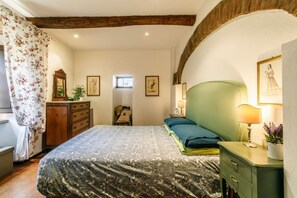 Un dormitorio con cama, cómoda, lámpara y fotografías enmarcadas en la pared.