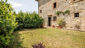 A stone building with a garden, a door, and windows.