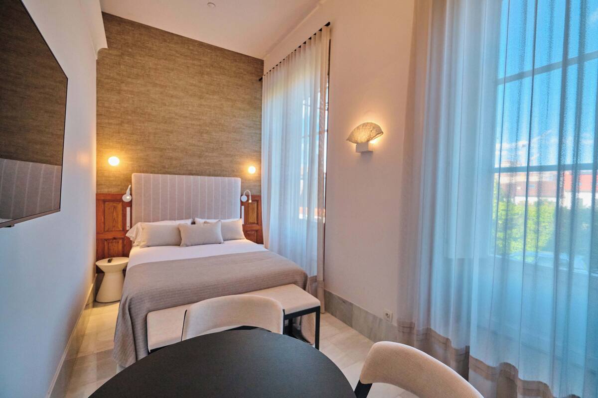Une chambre d’hôtel avec un grand lit, des tables de chevet, un bureau et une chaise.