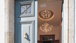 Een statig entree met een blauwe deur, een decoratieve plafondlamp en een vloer met patroon.