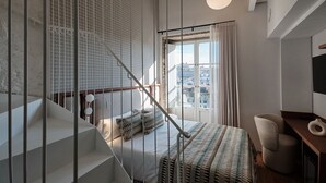Een moderne slaapkamer met een bed, een bureau en een trap.