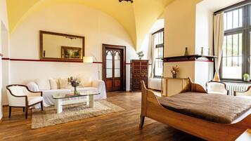 A spacious room with a wooden bed, a white sofa, a glass coffee table, and a large mirror.