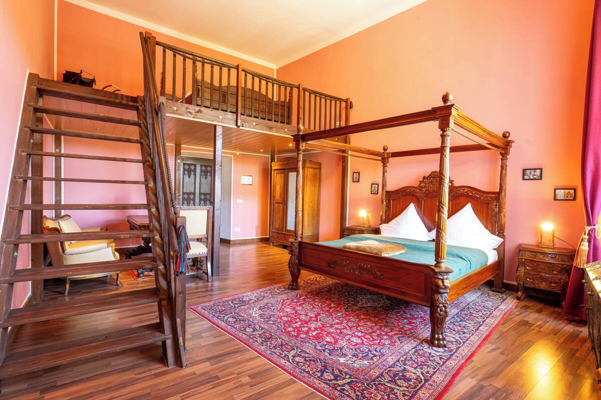 Una cama con dosel de madera y un tapete rojo con estampado.