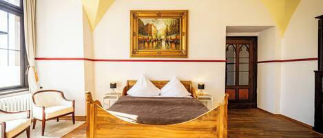 Un dormitorio con cama de madera, almohadas blancas, una franja roja en la pared, un cuadro sobre la cama y una ventana con cortinas.