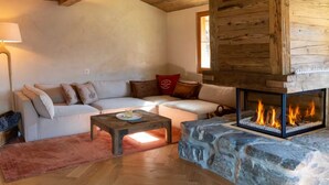 A cozy living room with a fireplace, a sofa, a coffee table, and a lamp. - Chalet Annabelle (Sankt Stephan)