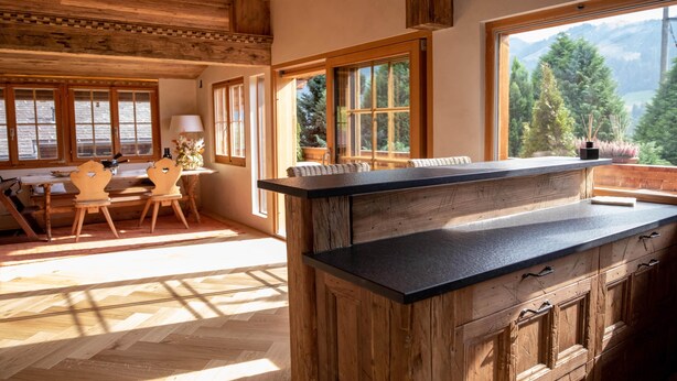 A rustic kitchen with wooden cabinetry and a large window overlooking a mountainous landscape. - Chalet Annabelle (Sankt Stephan)