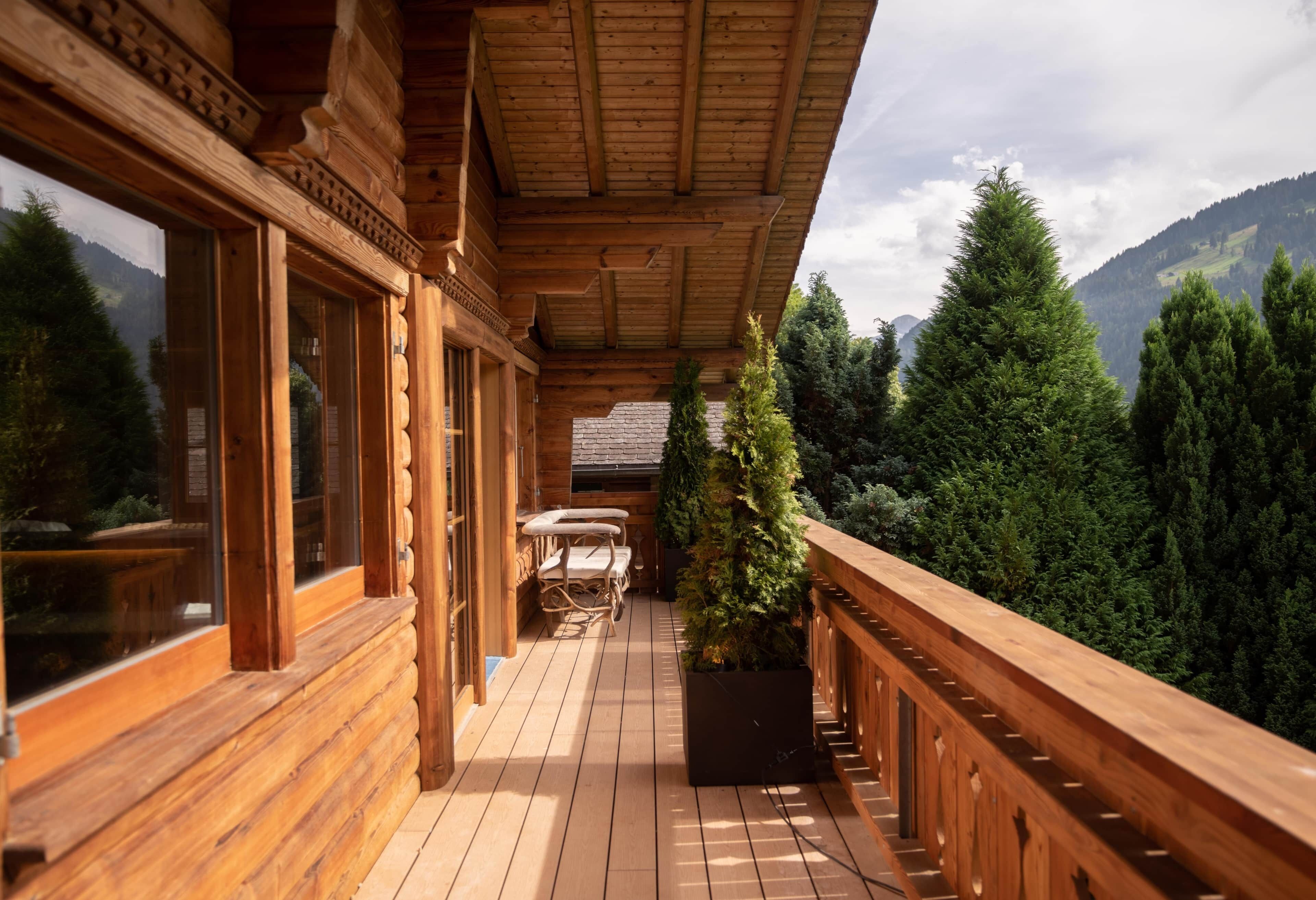A wooden balcony with a view of a forest and mountains.