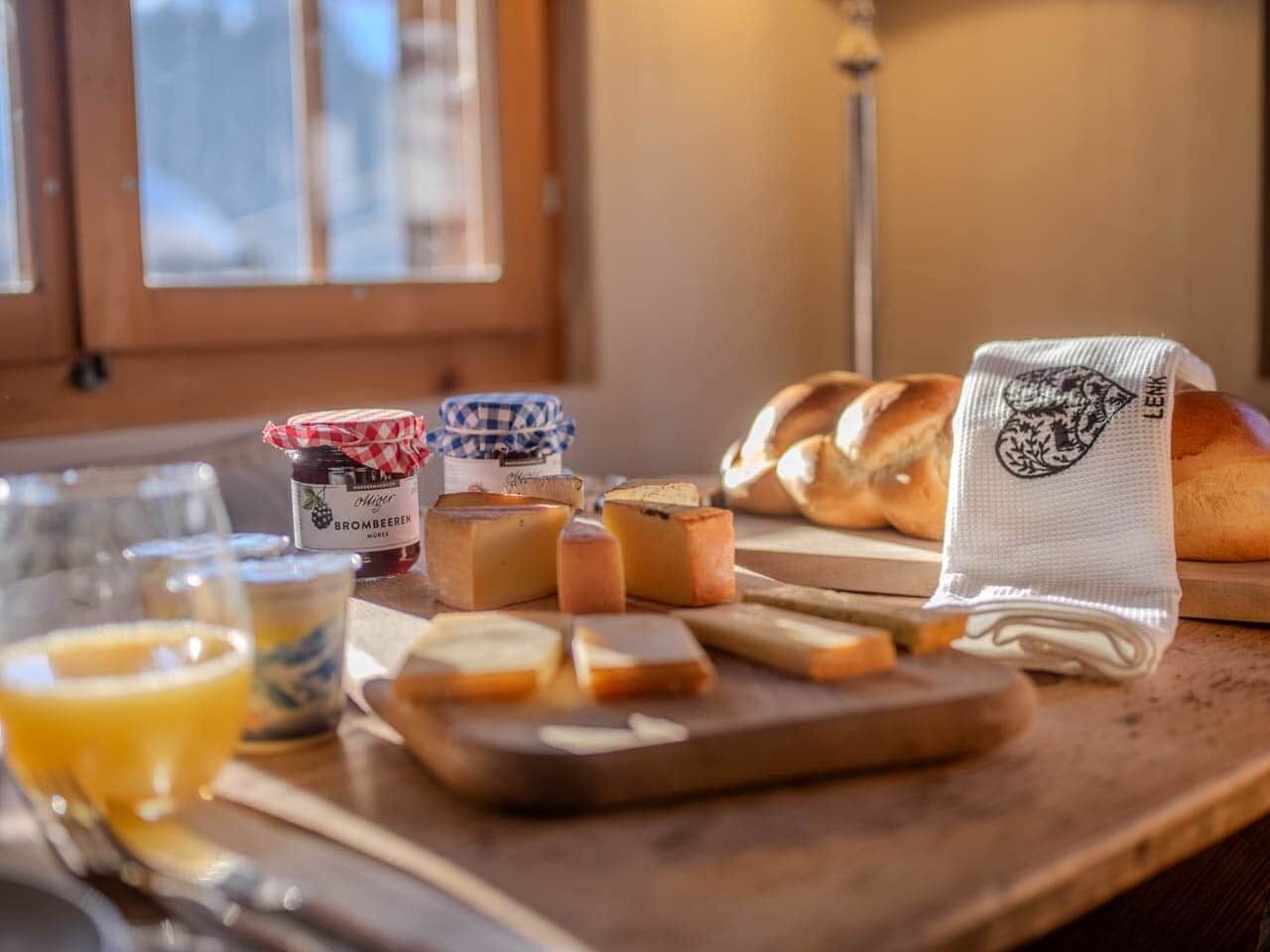 Een tafel met kaas, brood en een potje jam.