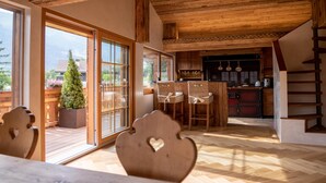 A wooden interior with a dining area, kitchen, and a view of the outdoors. - Chalet Annabelle (Sankt Stephan)
