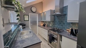 A modern kitchen with a gas stove, oven, and a clock on the wall. - Pet friendly comfortable Victorian terraced home (Cambridge)