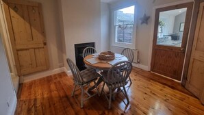 A dining area with a round table, four chairs, a fireplace, a window, and a door. - Pet friendly comfortable Victorian terraced home (Cambridge)