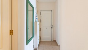 A narrow hallway with a white door at the end, a green-framed mirror on the left, and a small shelf with items on the right. - Beachfront House in Las Palmas With Sea Views (Las Palmas de Gran Canaria)